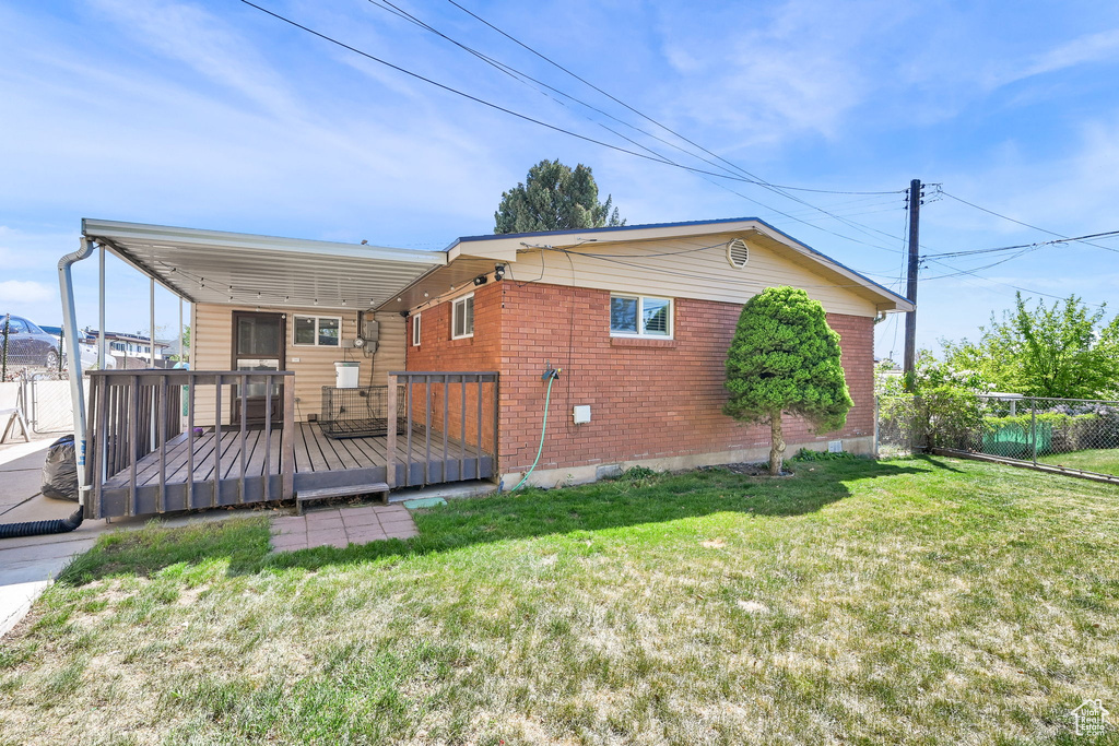 Rear view of property with fence, a yard, a deck, and brick siding