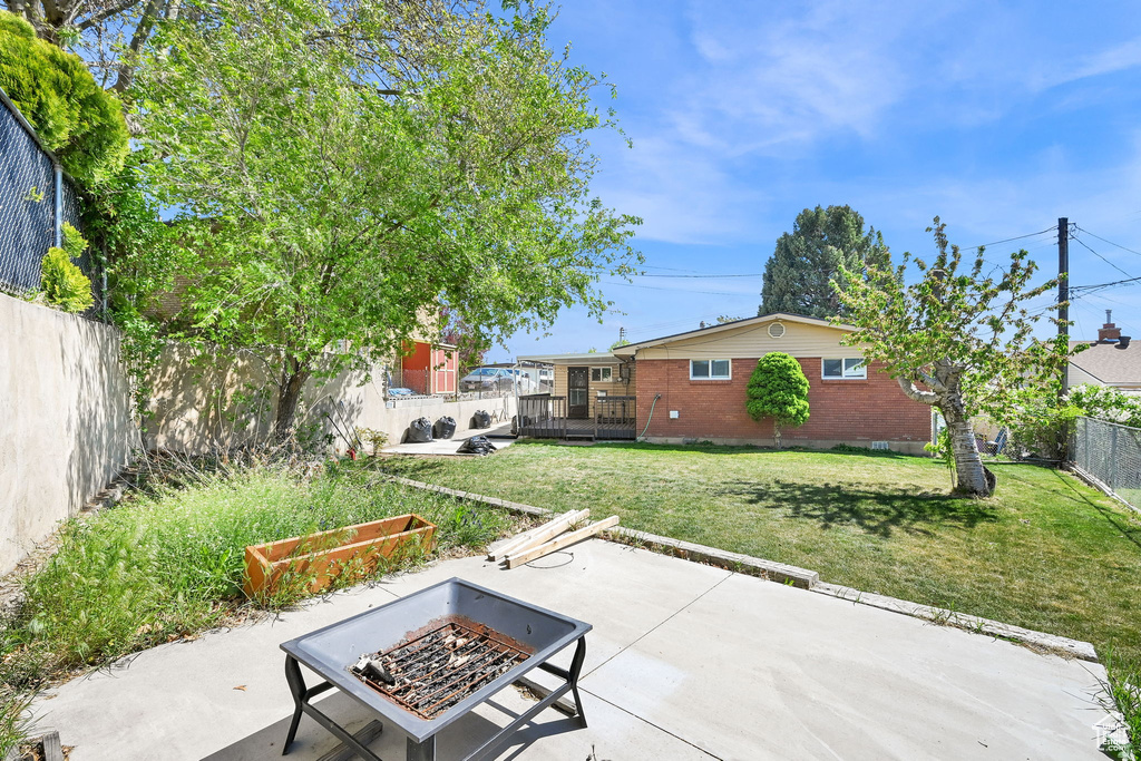 View of patio with a deck, a fenced backyard, and an outdoor fire pit