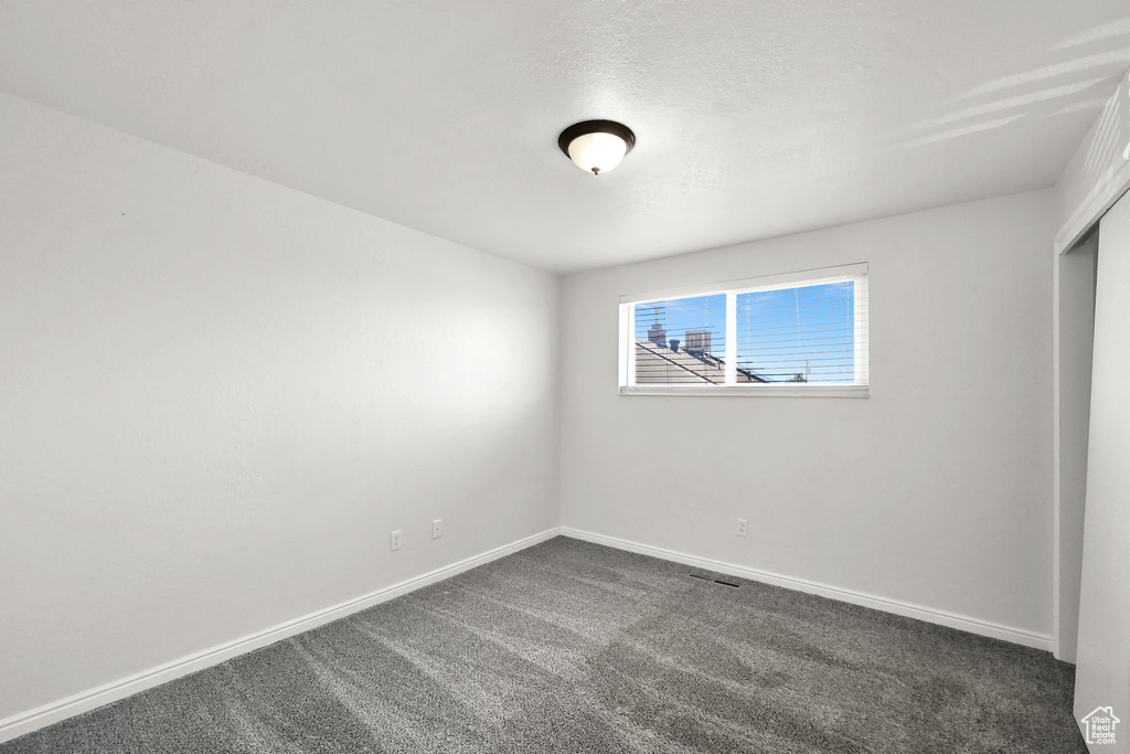 Spare room featuring baseboards and dark colored carpet