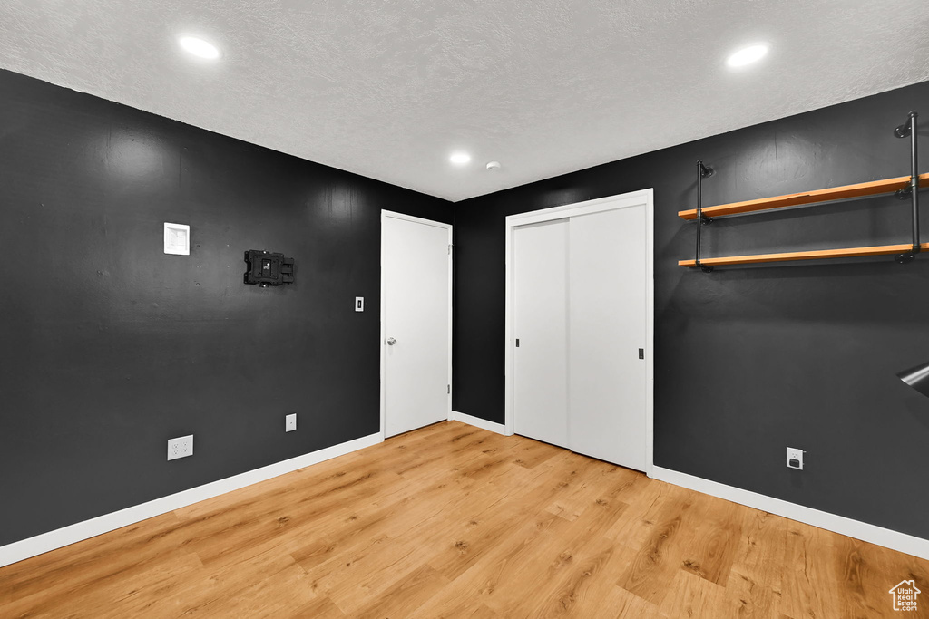 Unfurnished bedroom featuring a closet, baseboards, recessed lighting, light wood-type flooring, and a textured ceiling