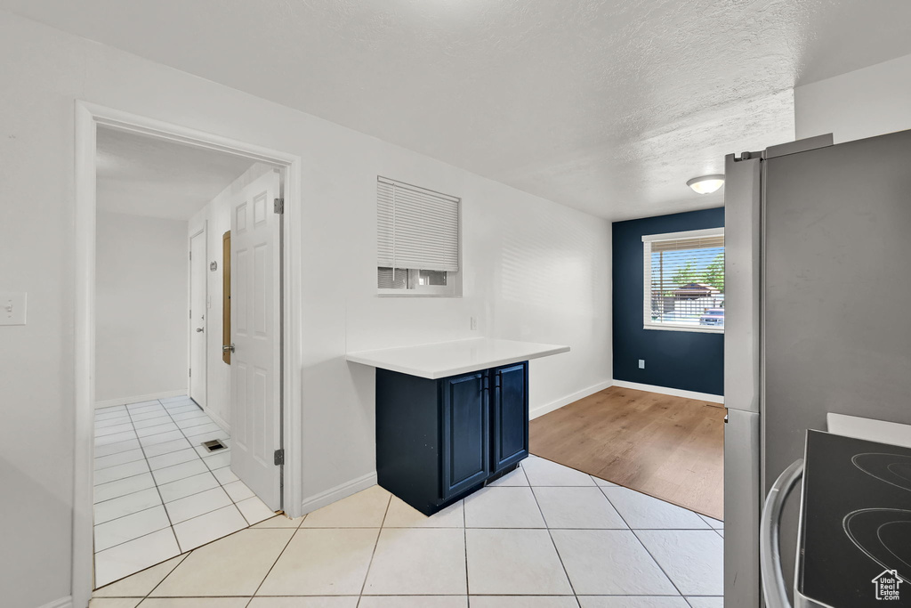 Kitchen with range with electric cooktop, blue cabinetry, light tile patterned floors, light countertops, and baseboards