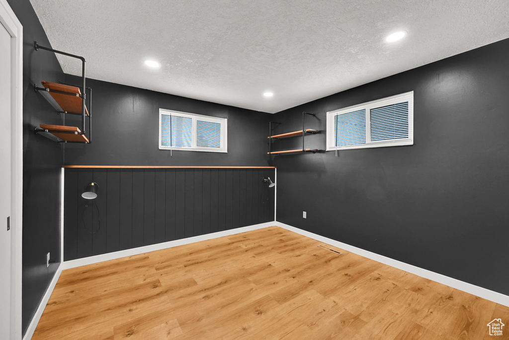 Basement with recessed lighting, a textured ceiling, visible vents, and light wood-type flooring