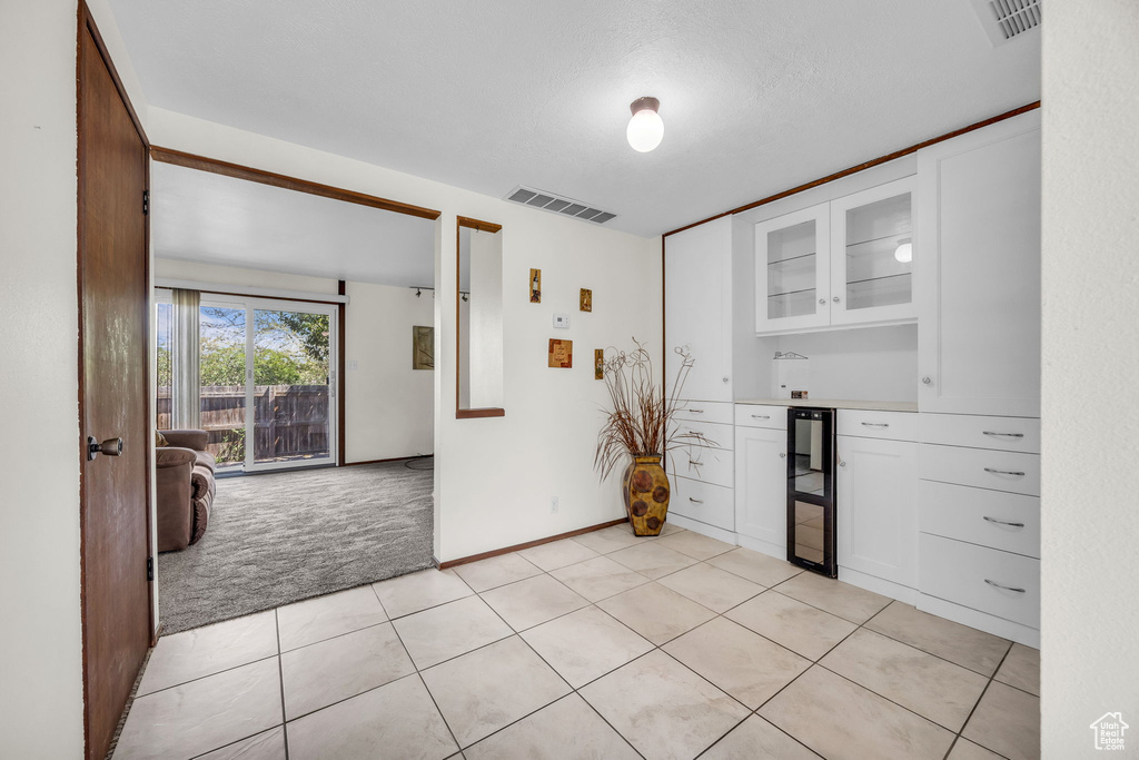 Kitchen featuring glass insert cabinets, visible vents, white cabinetry, and light carpet