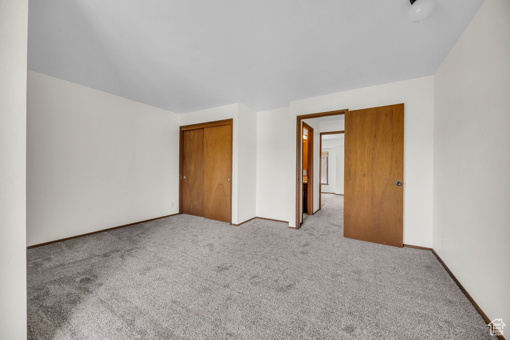 Unfurnished bedroom with a closet, carpet floors, and baseboards