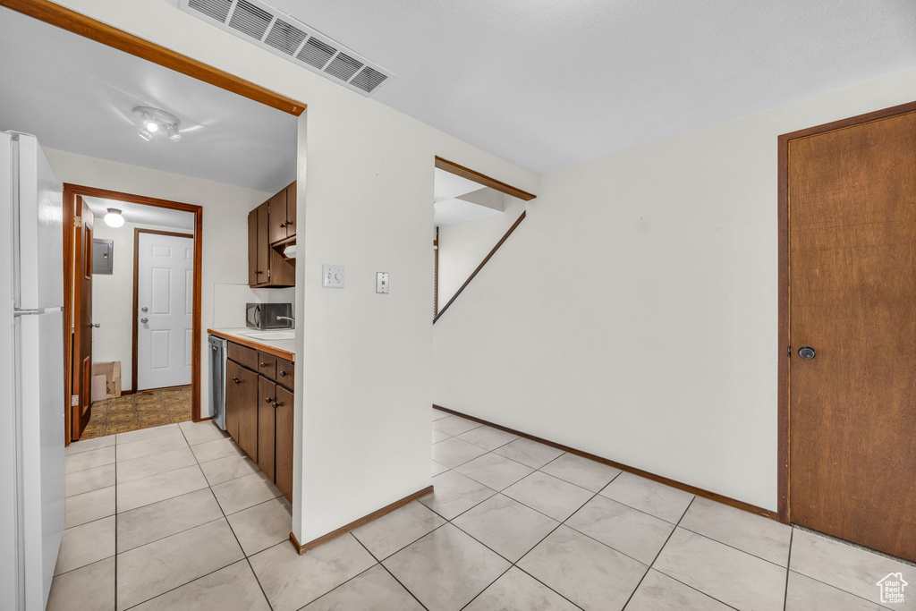 Kitchen with freestanding refrigerator, light tile patterned floors, light countertops, dishwasher, and visible vents