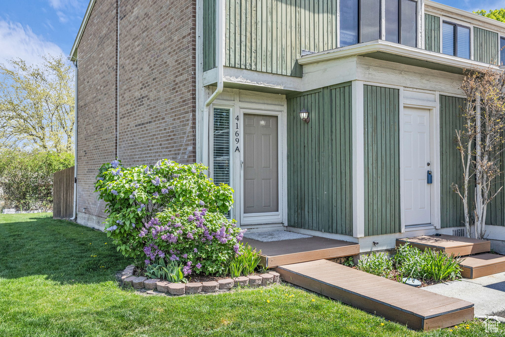 Entrance to property with brick siding and a lawn