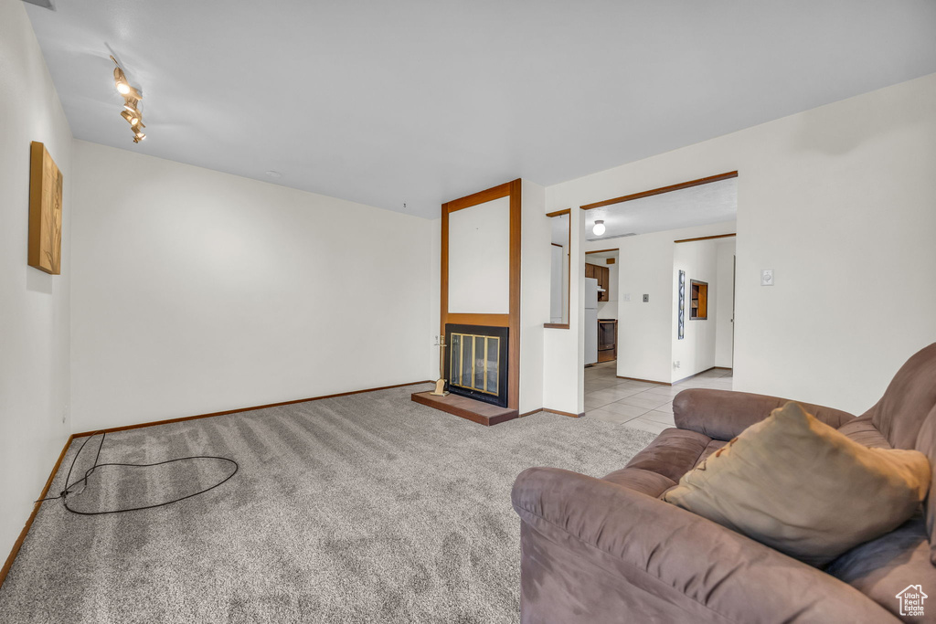 Carpeted living room with baseboards and a glass covered fireplace