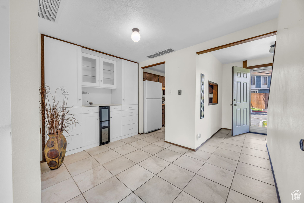 Kitchen with white cabinetry, visible vents, glass insert cabinets, and freestanding refrigerator