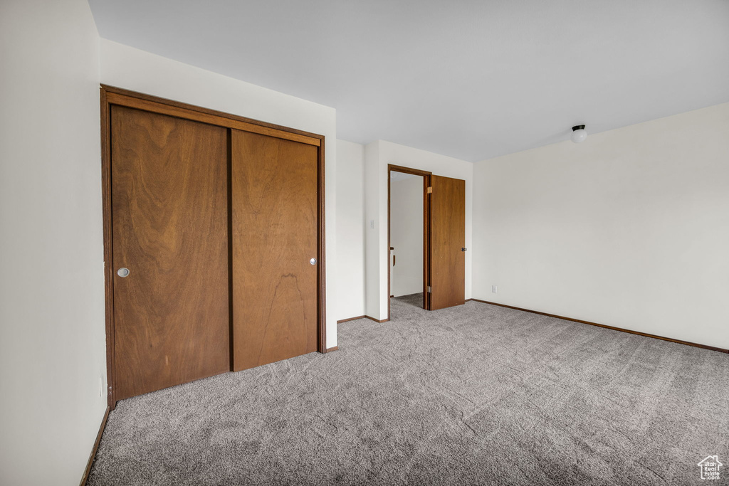 Unfurnished bedroom featuring baseboards, a closet, and carpet flooring