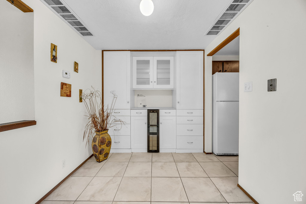Kitchen featuring visible vents, white cabinets, and freestanding refrigerator