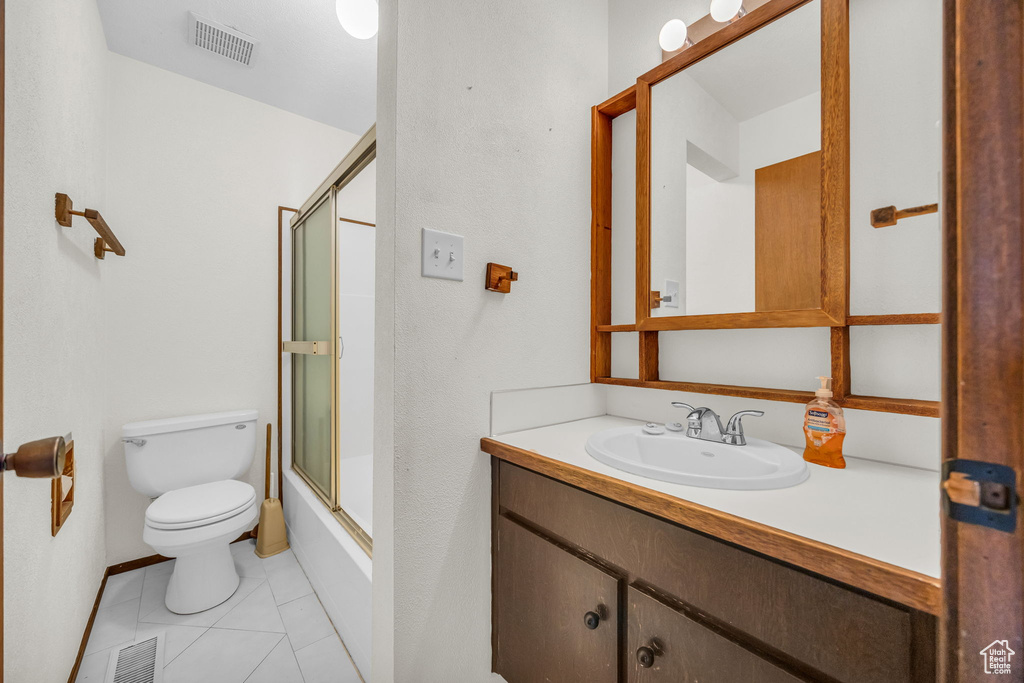 Full bath with toilet, visible vents, bath / shower combo with glass door, and vanity