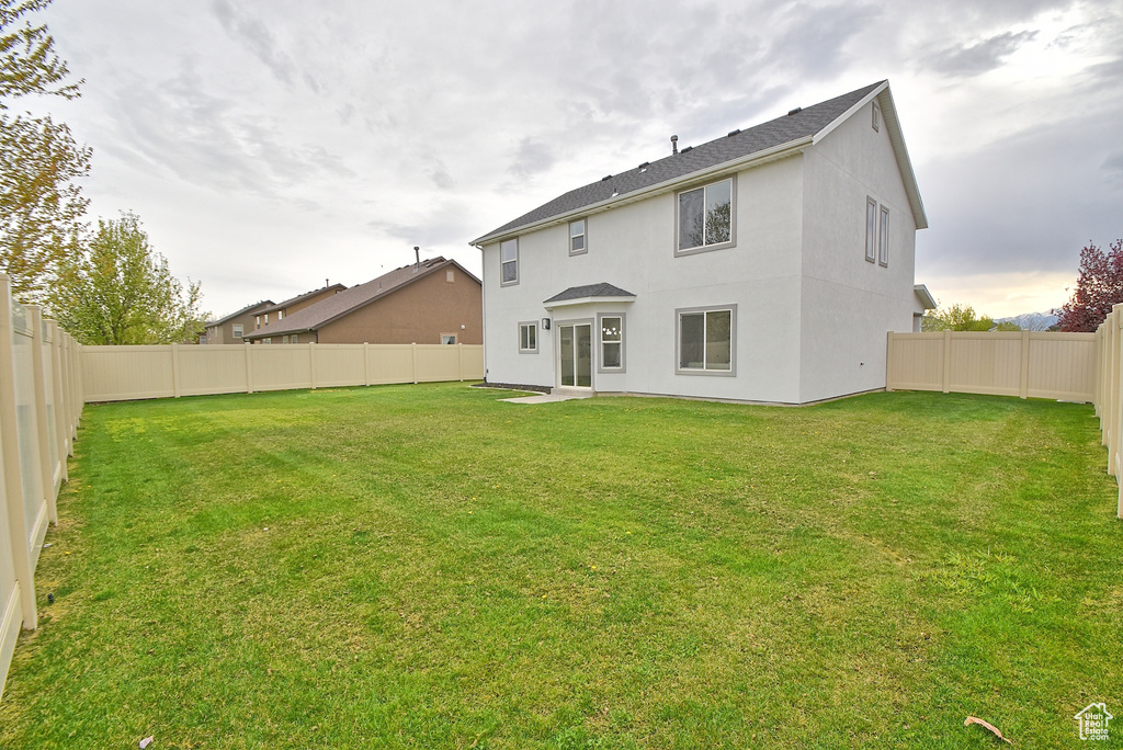 Rear view of property featuring a fenced backyard, stucco siding, and a yard