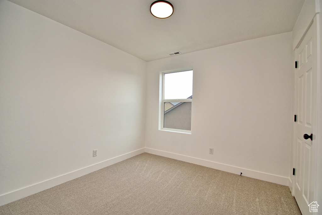 Unfurnished room with baseboards, visible vents, and light carpet