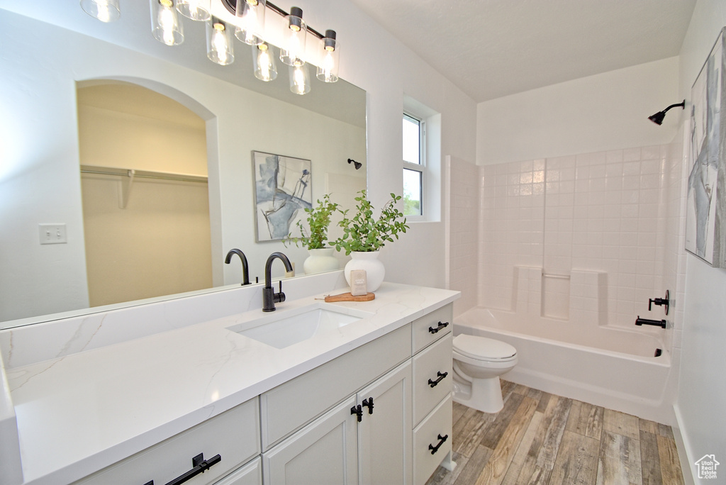 Bathroom featuring wood finished floors, toilet, shower / washtub combination, vanity, and a spacious closet