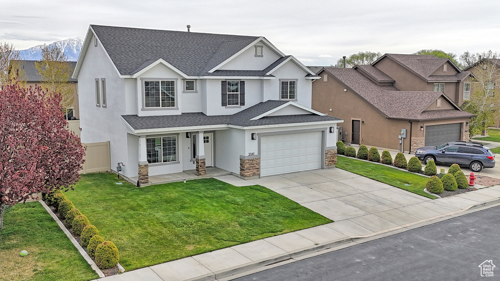 Traditional-style home with stucco siding, a shingled roof, stone siding, concrete driveway, and an attached garage