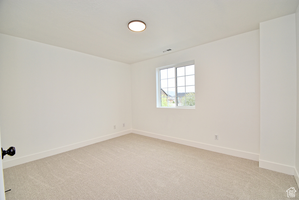 Empty room with visible vents, baseboards, and light carpet