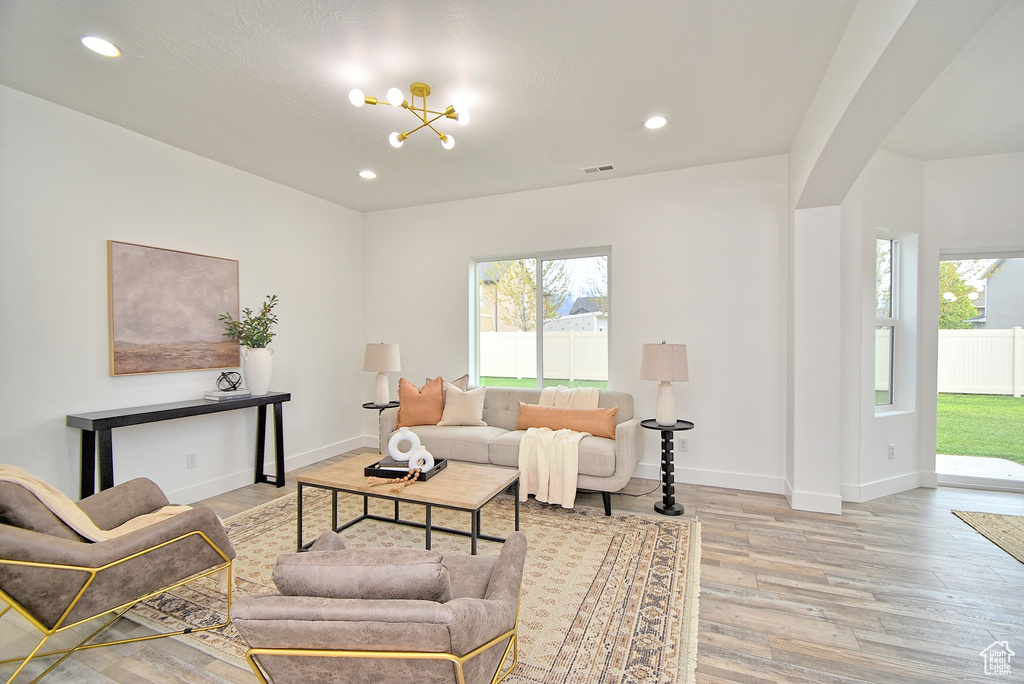 Living area featuring a wealth of natural light, visible vents, light wood finished floors, and a notable chandelier