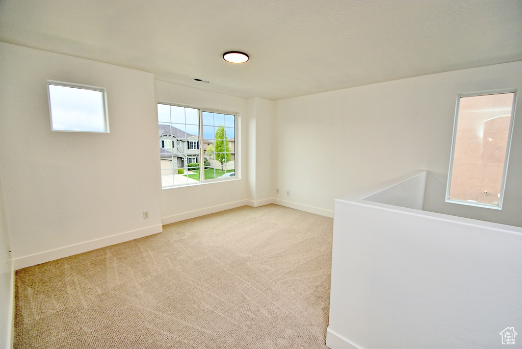 Unfurnished room featuring baseboards, visible vents, and light carpet