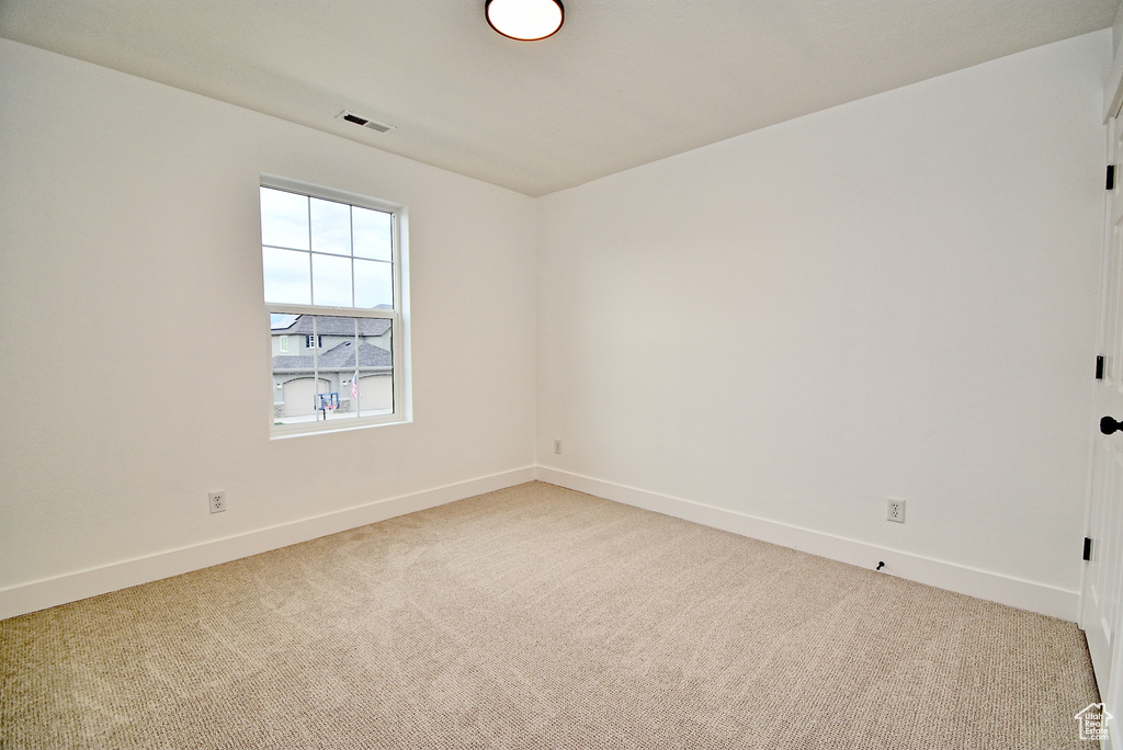 Spare room with visible vents, light colored carpet, and baseboards