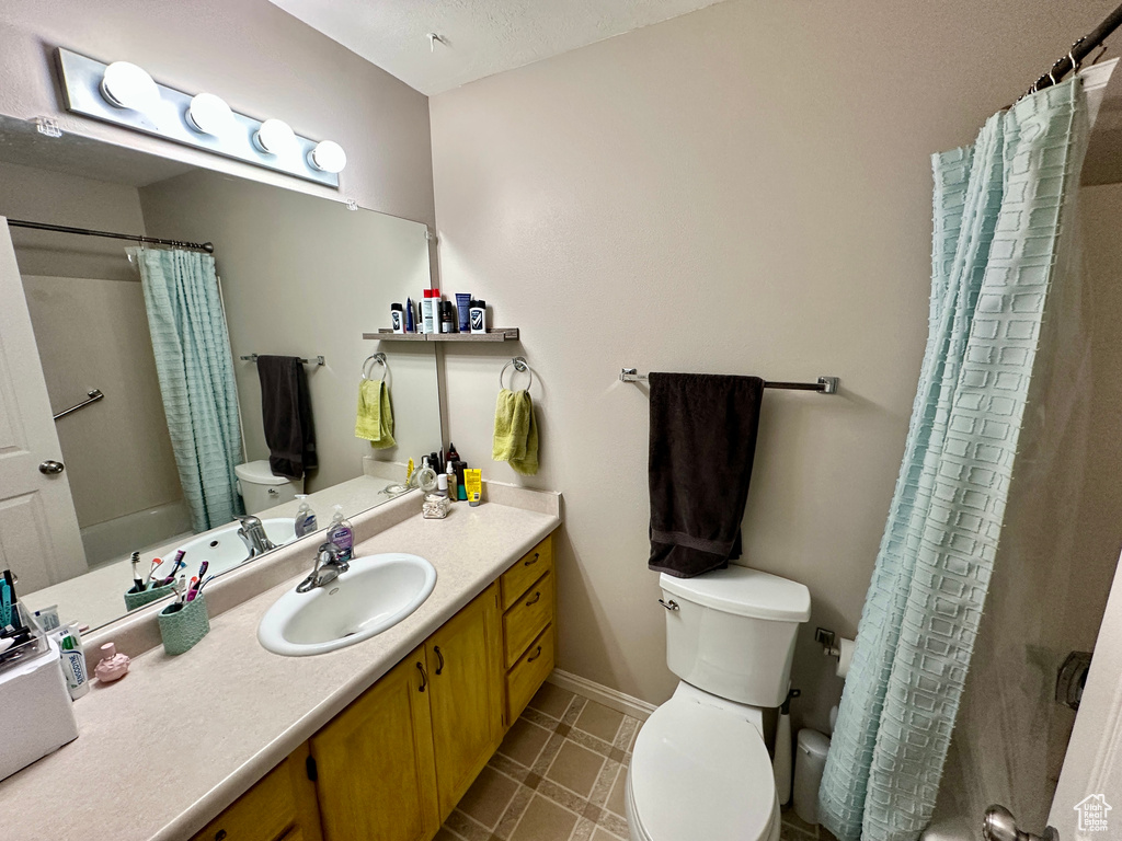Bathroom with baseboards, shower / bath combo, toilet, and vanity