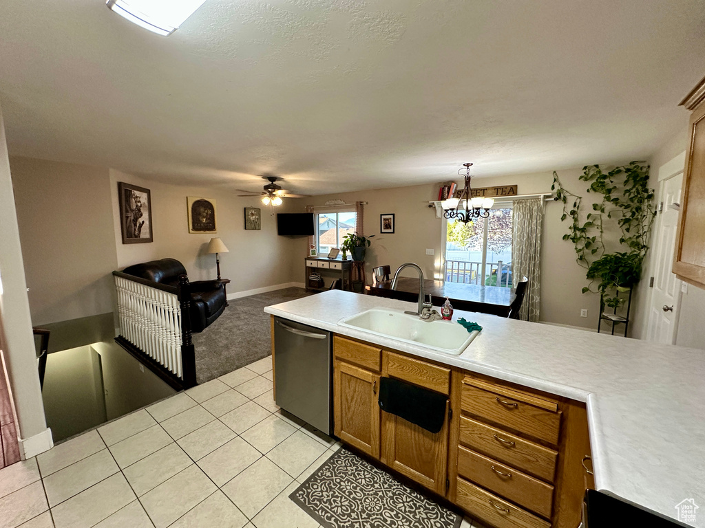 Kitchen with light countertops, brown cabinets, ceiling fan with notable chandelier, dishwasher, and a sink