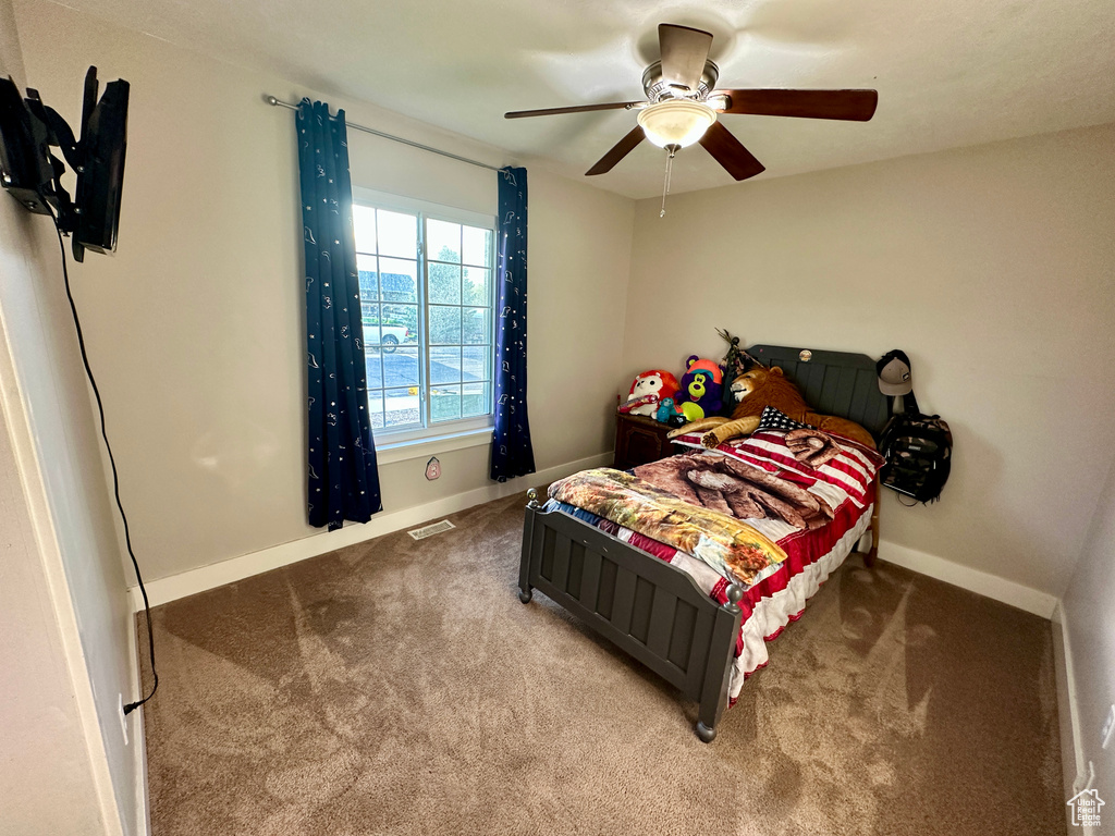 Carpeted bedroom with visible vents, a ceiling fan, and baseboards