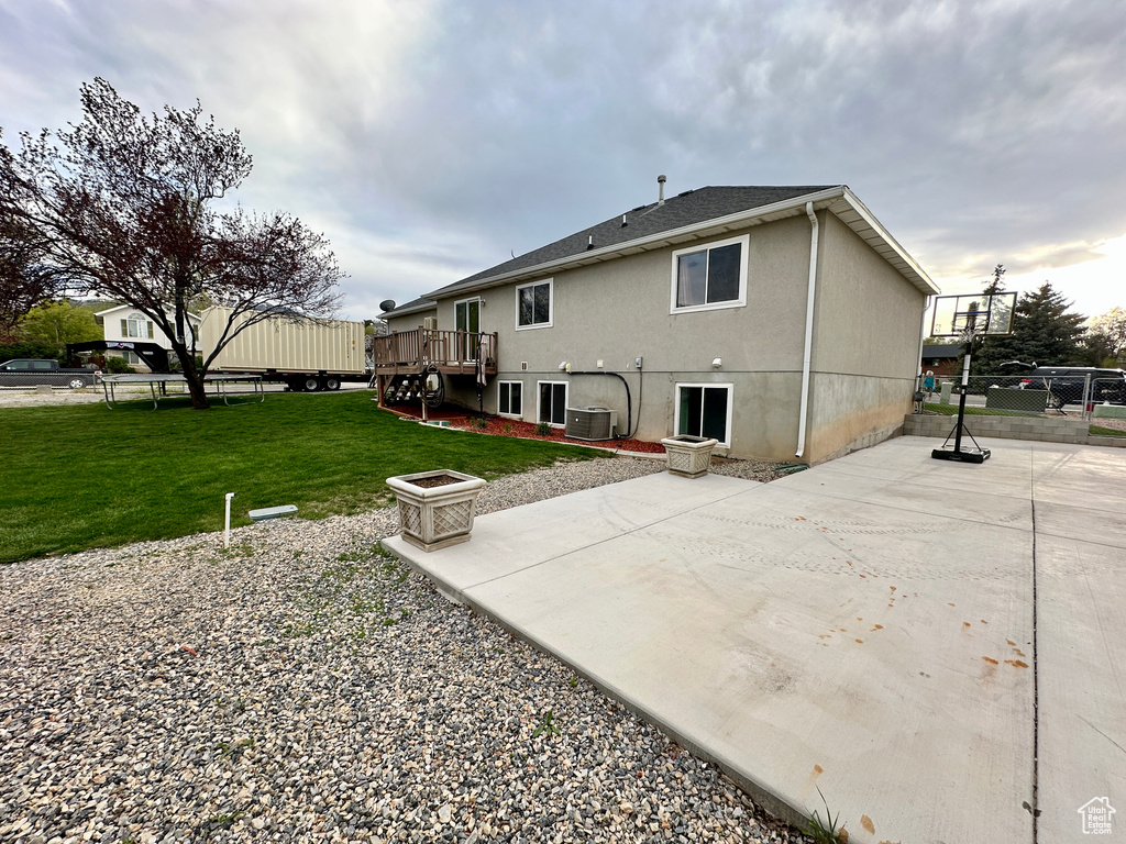 Back of property featuring a deck, fence, a yard, and a patio area