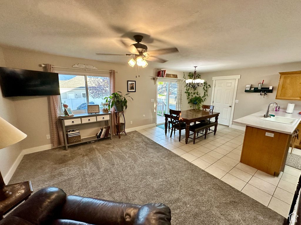Living room featuring baseboards, light tile patterned floors, ceiling fan with notable chandelier, and a textured ceiling