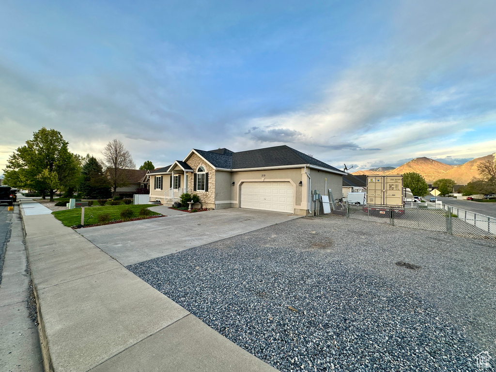 Single story home with a garage, fence, stucco siding, and driveway