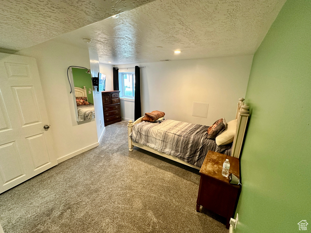 Carpeted bedroom with a textured ceiling and baseboards