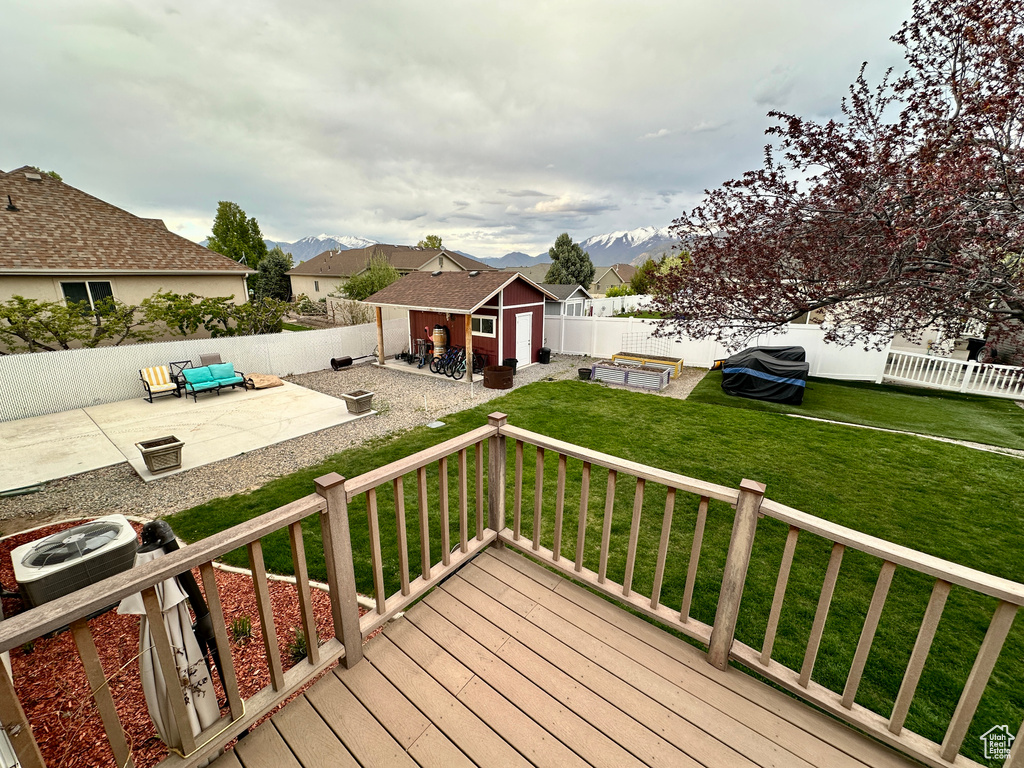 Wooden terrace featuring an outdoor structure, a patio, a storage shed, a yard, and a fenced backyard