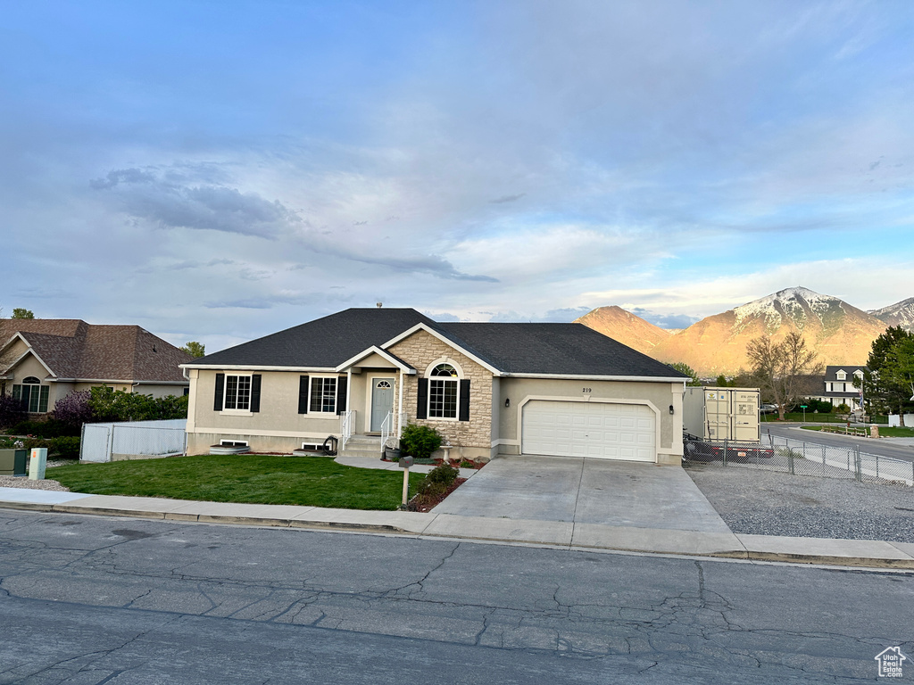 Single story home featuring fence, driveway, a mountain view, a front lawn, and an attached garage