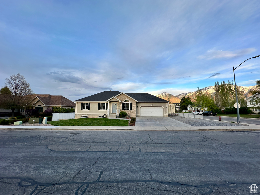 Single story home featuring a garage, a mountain view, fence, and driveway