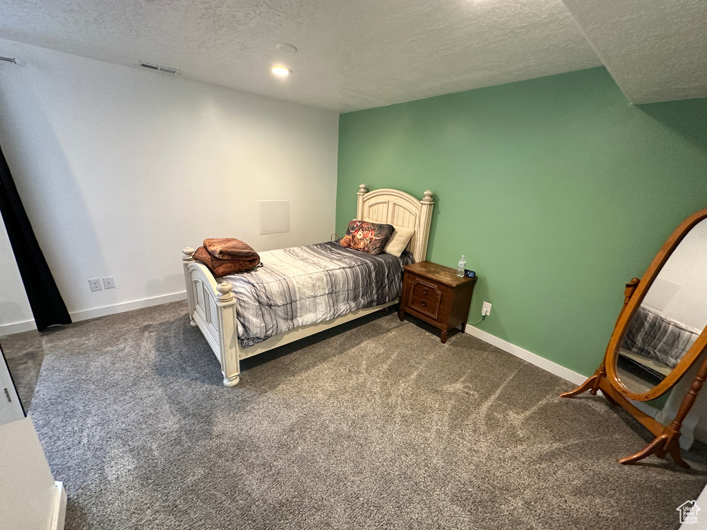 Bedroom with a textured ceiling, visible vents, and carpet floors