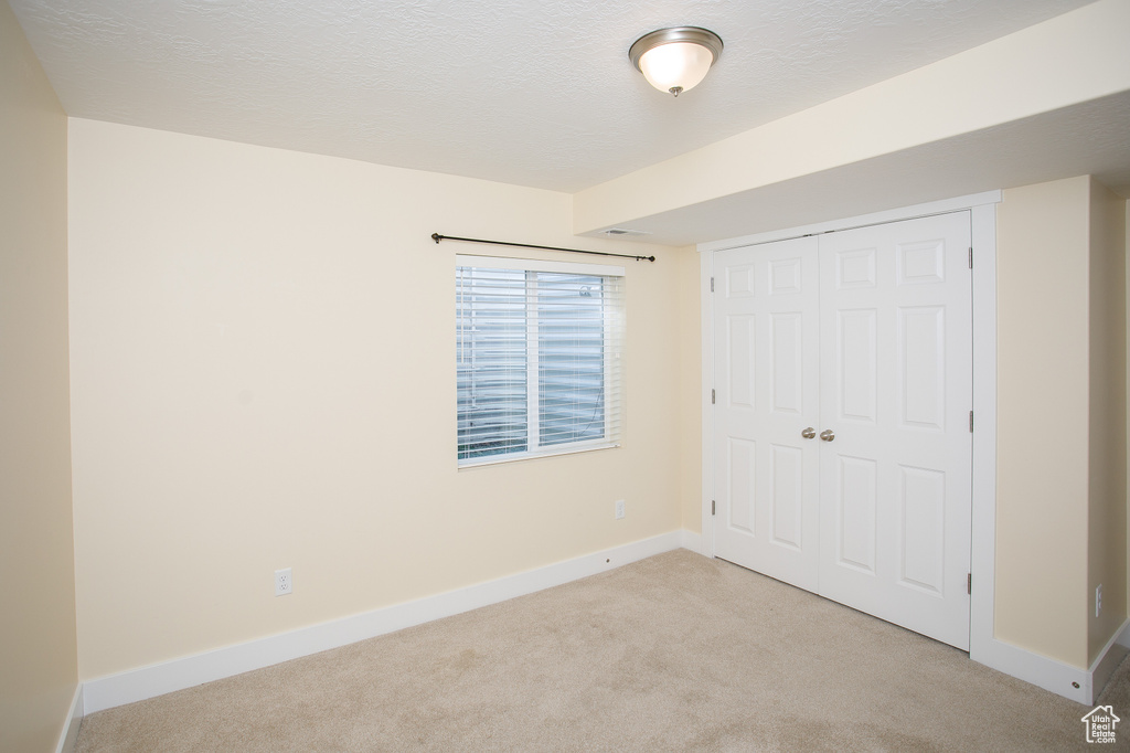 Unfurnished bedroom with baseboards, a closet, and light colored carpet