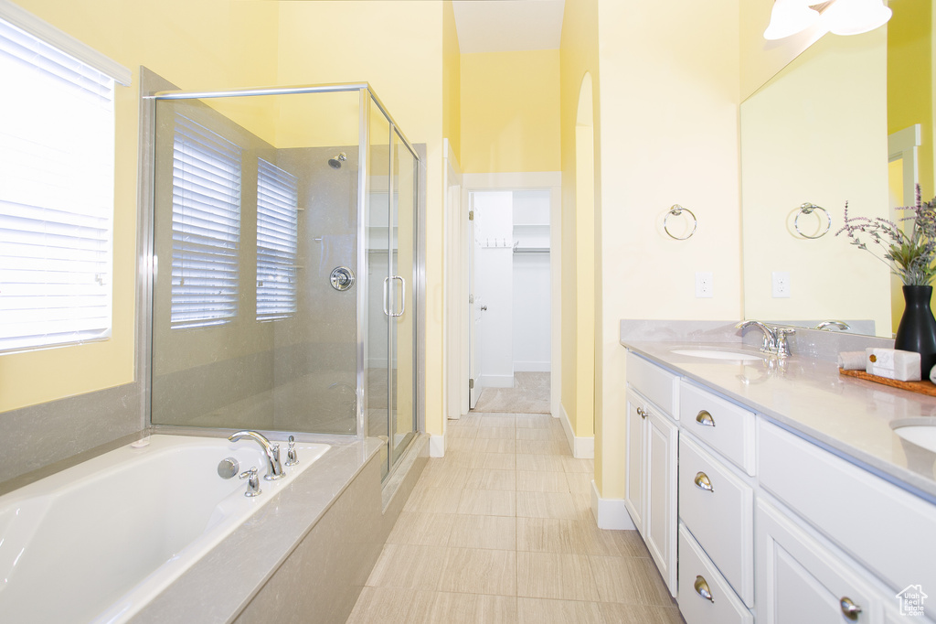 Full bath with a sink, double vanity, a stall shower, a spacious closet, and a garden tub