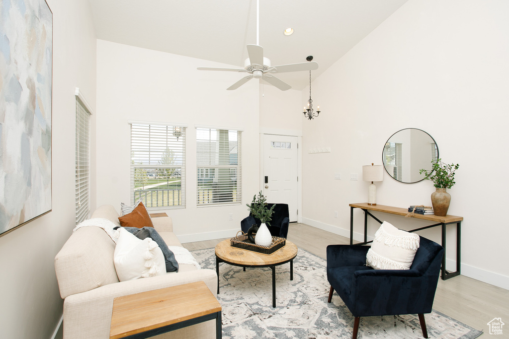 Living area featuring high vaulted ceiling, light wood finished floors, baseboards, and a ceiling fan