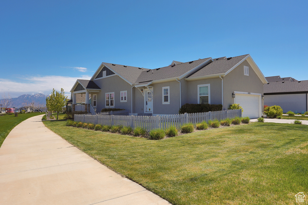 Single story home featuring stucco siding, fence, a mountain view, and a front yard