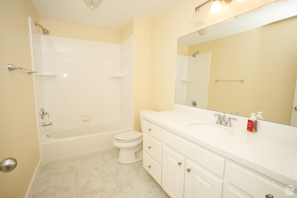 Bathroom featuring marble finish floor, shower / bathtub combination, toilet, vanity, and baseboards