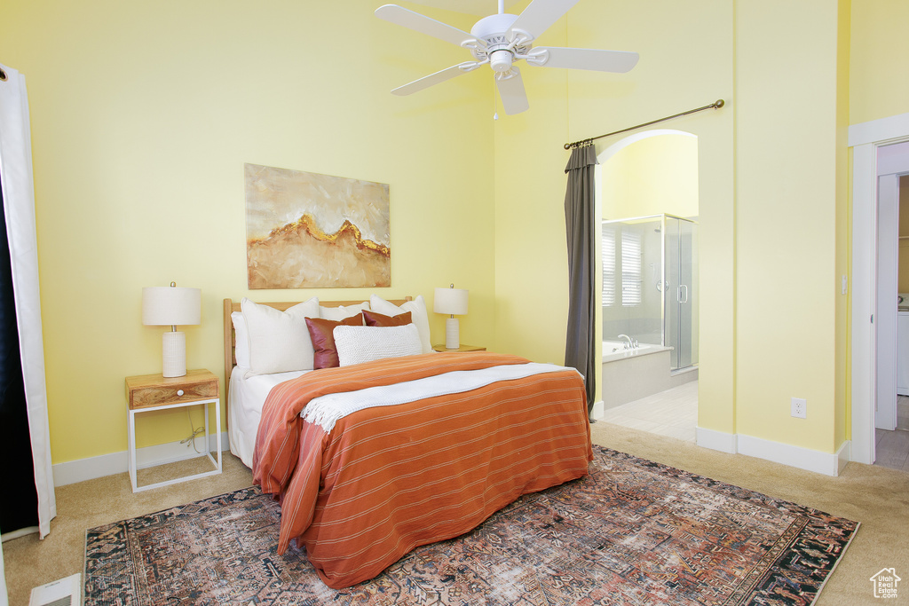 Carpeted bedroom with baseboards, ensuite bathroom, a towering ceiling, and ceiling fan