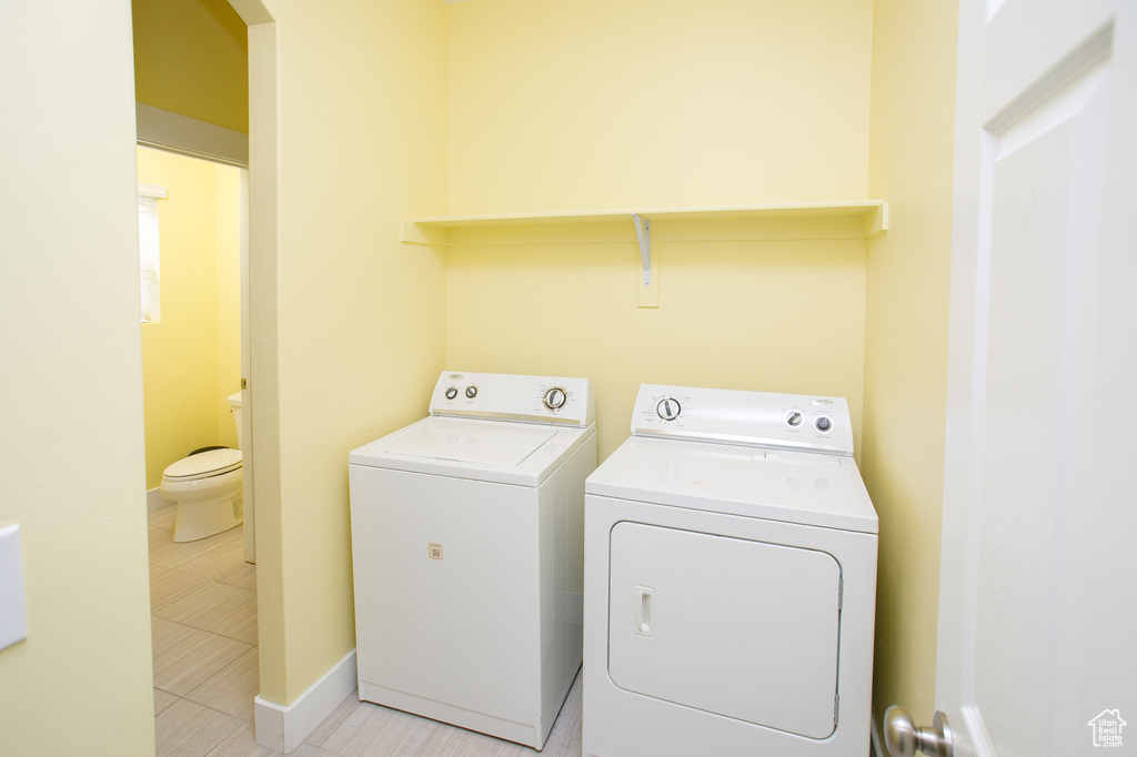 Laundry room with baseboards, washer and dryer, and light tile patterned floors