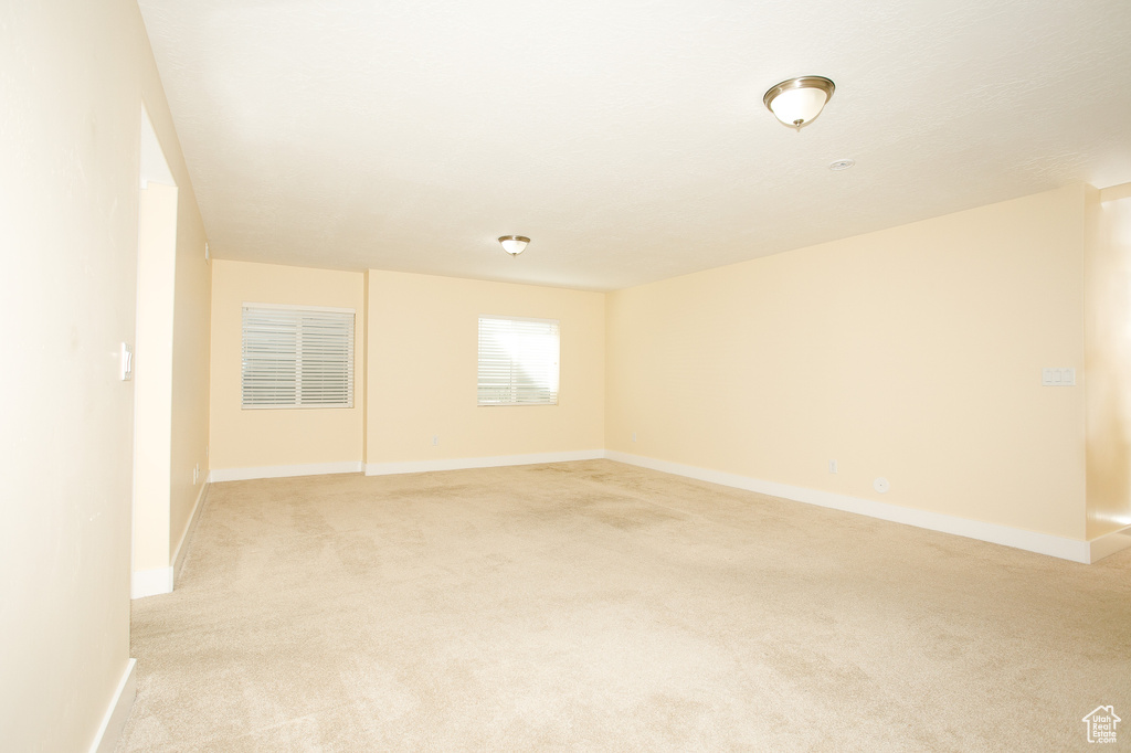 Empty room with baseboards and light colored carpet