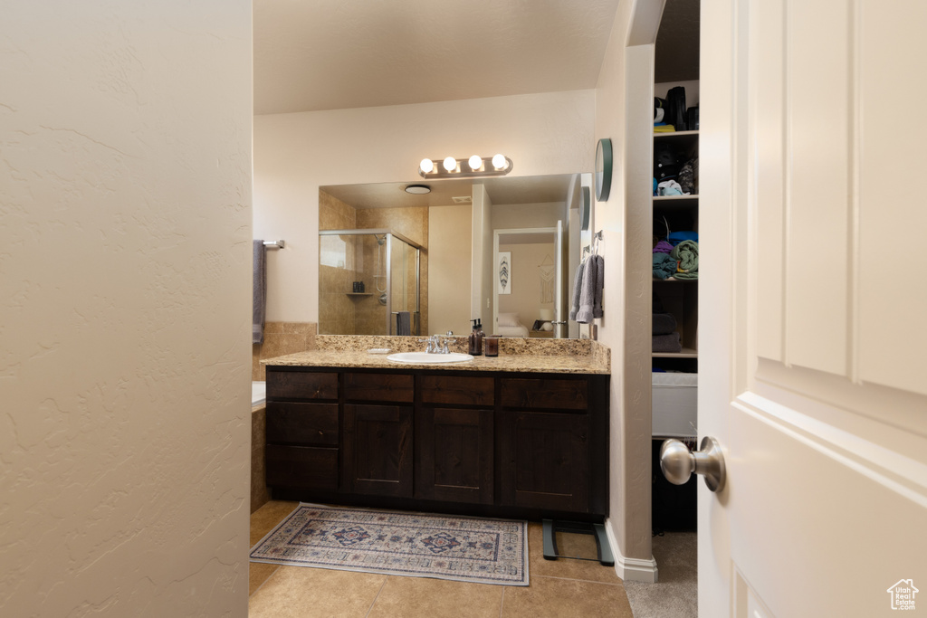 Full bathroom with vanity, tile patterned flooring, a stall shower, and a textured wall