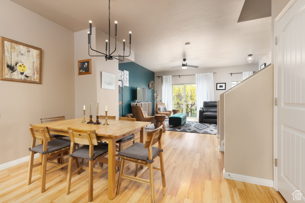 Dining space with baseboards, light wood finished floors, and ceiling fan with notable chandelier