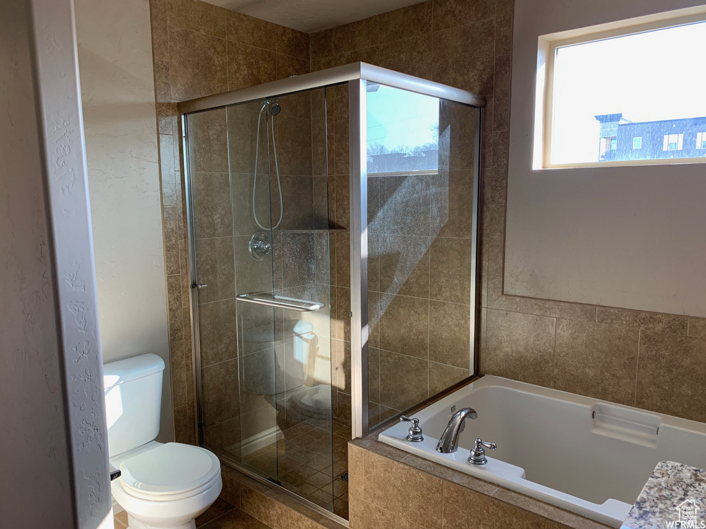 Bathroom featuring a garden tub, a stall shower, and toilet