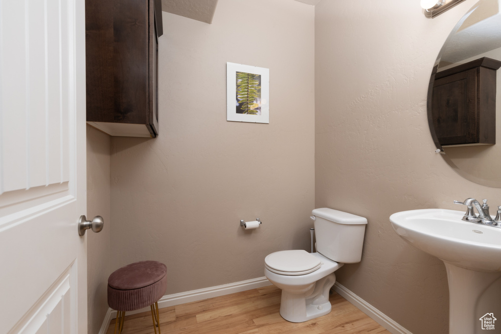 Bathroom featuring a sink, baseboards, toilet, and wood finished floors