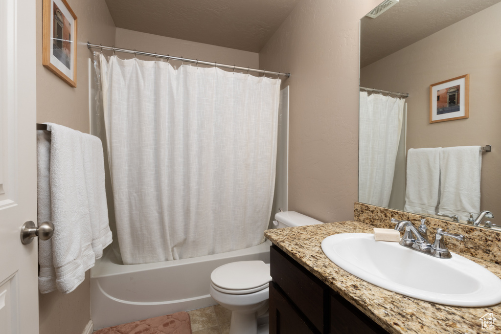 Bathroom featuring toilet, visible vents, shower / bathtub combination with curtain, and vanity