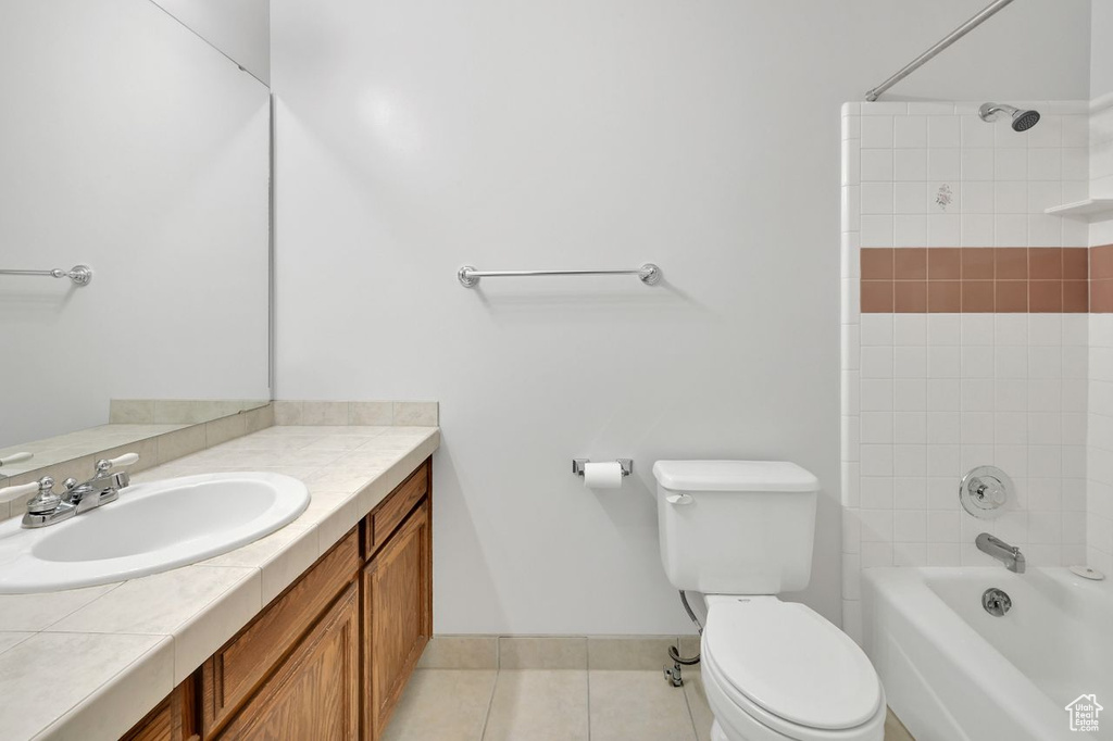 Bathroom featuring vanity, shower / bath combination, toilet, baseboards, and tile patterned flooring
