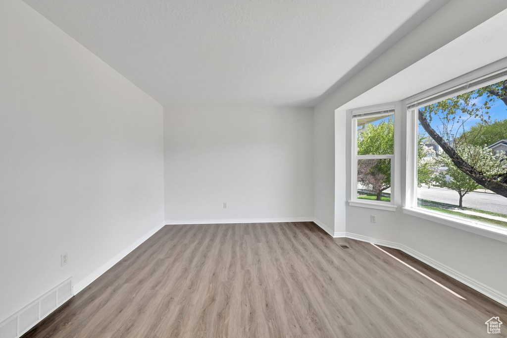 Spare room featuring baseboards, visible vents, and wood finished floors