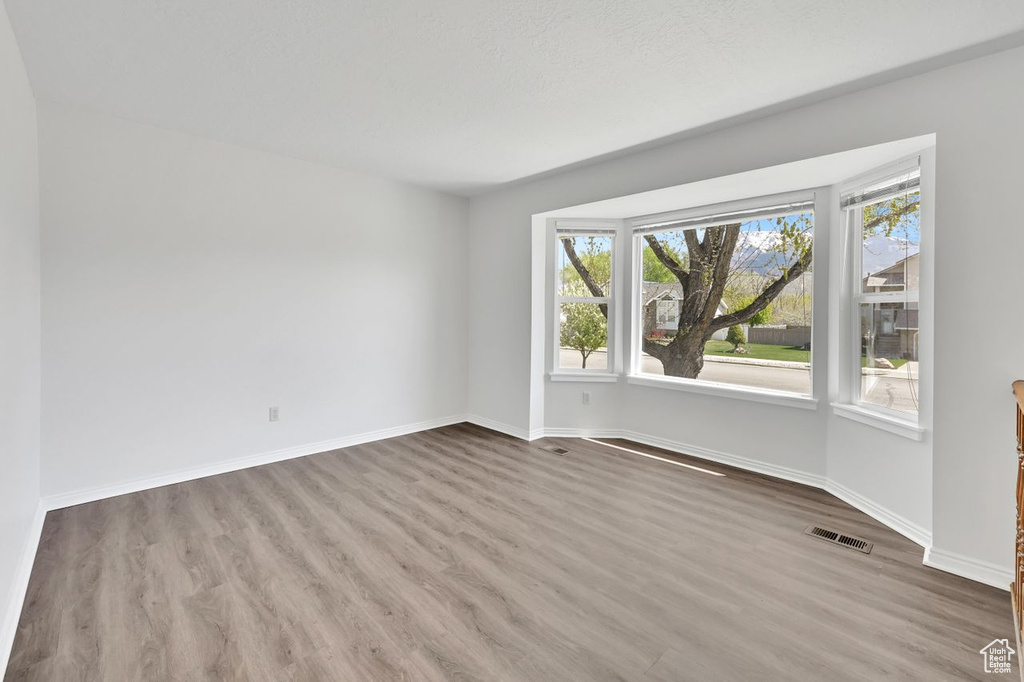 Spare room featuring wood finished floors, visible vents, and baseboards